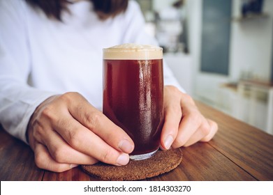 Someone Holding A Glass Of Nitro Cold Brew Coffee. Nitro Coffee Is Unique Type Of Coffee Is Cold-brewed And Infused With Nitrogen Gas To Improve Both Its Taste And Texture.