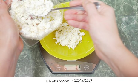 someone measures cottage cheese in electronic form in the kitchen. pour the croup into a deep round bowl, standing on a flat weighing platform