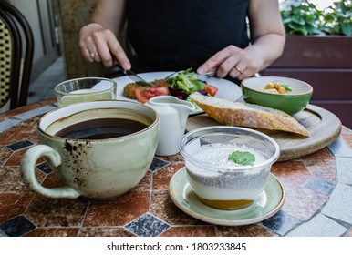 Someone Outdoor Is Not Eating Vegetarian Food: Vegetable And Beet Salad And Vegetable Cutlet, Lemonade, Bowl Of Hummus And A Piece Of Bread, Cup Of Coffee And Dessert: Chia And Coconut Milk Mousse