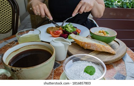 Someone Outdoor Is Not Eating Vegetarian Food: Vegetable And Beet Salad And Vegetable Cutlet, Lemonade, Bowl Of Hummus And A Piece Of Bread, Cup Of Coffee And Dessert: Chia And Coconut Milk Mousse