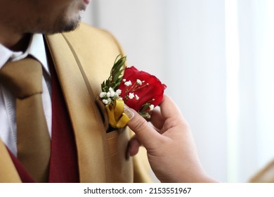 someone is pinning flowers on a man in a golden suit.