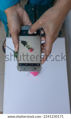 someone is taking a photo of flower with his cell phone camera