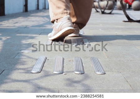 Someone is walking on braille bricks sidewalks wearing pink sneakers. [[stock_photo]] © 