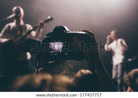 Someone's dslr camera with the video record mode on a concert with the live view picture on a screen. Music band on a stage as an object of shooting