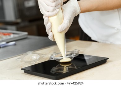 Something tasty. Closeup cropped shot of a cook squeezing the cream out of the pastry bag into a mold - Powered by Shutterstock