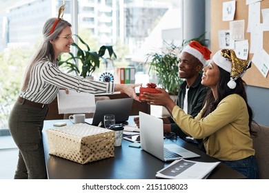 Sometimes All That Can Save Us Is Sensitivity And Compassion. Shot Of A Group Of Businesspeople Exchanging Christmas Gifts In A Modern Office.