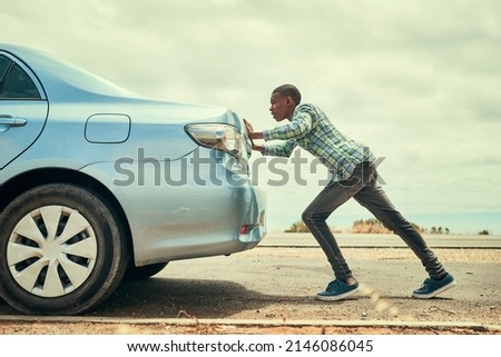 Sometimes youve gotta get out and push. Full length shot of a young man pushing his car along the road after breaking down.