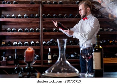 Sommelier Looking For Good Wine On The Storage In The Wine Cellar