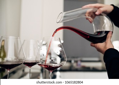 A sommelier pouring red wine into decanter