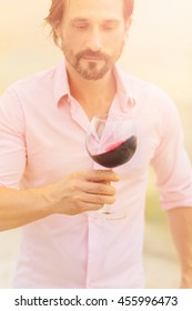 Sommelier Tasting Expensive Old Red Wine. Toned Picture Of Bearded Man In Pink Shirt Looking At Glass With Delicious Red Wine.