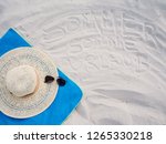 Sommer, Sonne Urlaub - german words for vacation written in the sand with a blue towel, a hat and sun glasses - travel concept