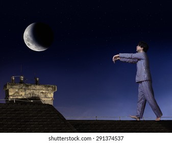 Somnambulist Walking On The Roof. Man In Pajamas Walks On Roof With Outstretched Hands. Moony In Pajamas Walks At Night On Roof Of A House Under Moonlight. Sleepwalker Walk Under The Moon.