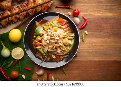 Somtum thai with crab.Papaya salad with crap and grilled chicken wings on wooden background. The famous local Thai street food dish with the taste of hot and spicy