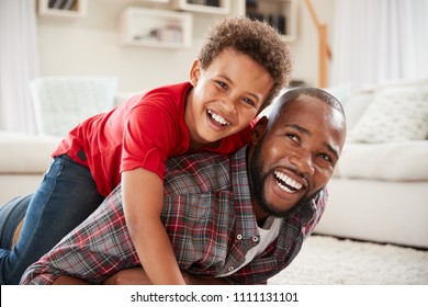 Son Climbs On Fathers Back As They Play Game In Lounge Together