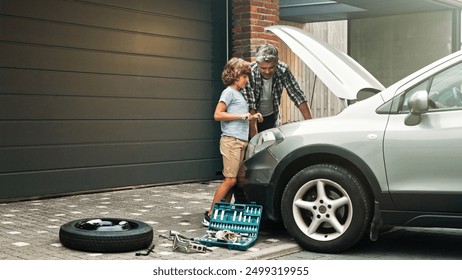 Son and dad are standing and fixing auto engine demages in the yard. Father teaches boy and showing him mechanical tools for repairing vehicles. Consept of successful fatherhood. - Powered by Shutterstock