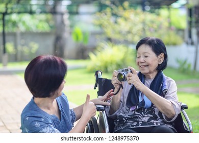 Son And Daughter In Law Looking After Elderly Mother In Backyard