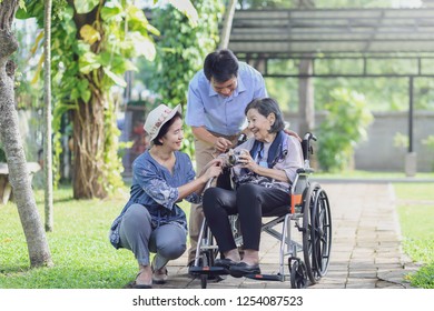 Son And Daughter In Law Looking After Elderly Mother In Backyard