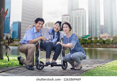 Son And Daughter In Law Looking After Elderly Mother In Backyard