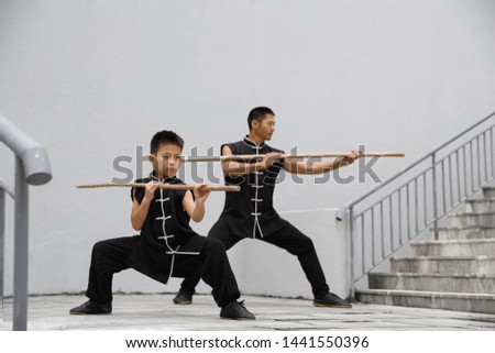 Son and father are engaged in Wushu. Morning Wushu training in the city.