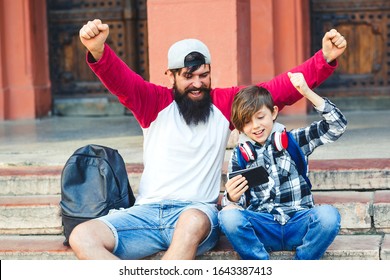 Son With Father Watching Football, Baseball, Basketball On Smarthone Outdoors. Dad With Kid Having Fun Together. Excited Family, Celebrating, Rejoice At Goal, Victory Of Favorite Team. 