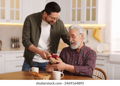 Son giving gift box to his dad at home - Powered by Shutterstock