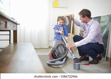 Son Helping Father To Mend Broken Vacuum Cleaner