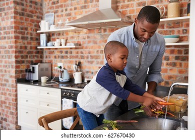 Son Helping Father To Prepare Vegetables For Meal In Kitchen