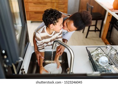 Son is helping mother in the Kitchen, Washing Dishes. African American family. - Powered by Shutterstock