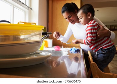 Sohn, der Mutter hilft, Geschirr im Küchenschacht zu waschen