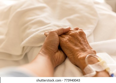 Son holding father is hand with saline intravenous in the hospital room - Powered by Shutterstock