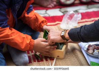 The son learning to make Chung cake by hands with his father closeup, Chung cake is the most important traditional Vietnamese lunar New Year (Tet) food.