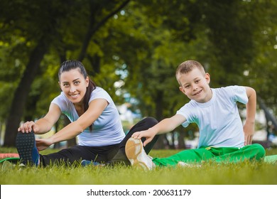 son and mother are doing exercises in the summer park - Powered by Shutterstock