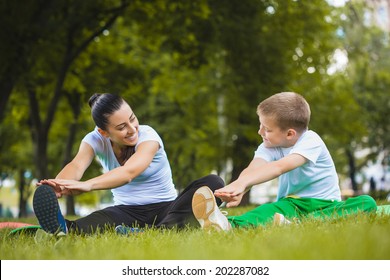 son and mother are doing exercises in the summer park - Powered by Shutterstock