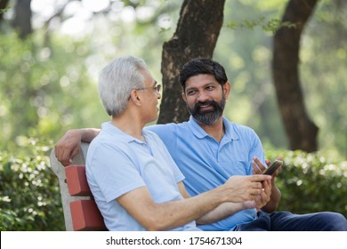 Son With Old Father Talking At Public Park 