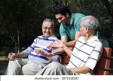 Son With Old Father Using Digital Tablet At Park