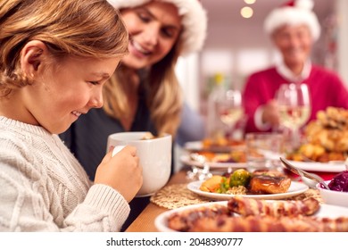 Son Pouring Gravy Onto His Food As Family Eat Christmas Meal