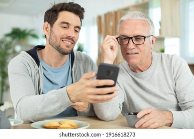 son show his phone to his mature father - Powered by Shutterstock