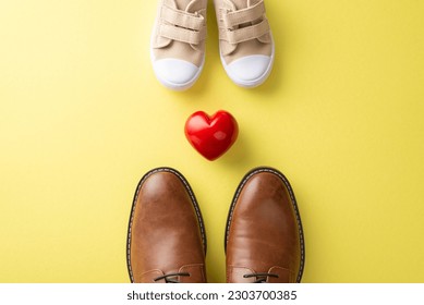 Son surprises Dad on Father's Day. Top square view of father's leather shoes, son's small sneakers and heart between them on yellow backdrop - Powered by Shutterstock