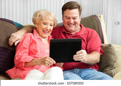 Son Teaching His Elderly Mother To Use A New Tablet PC.