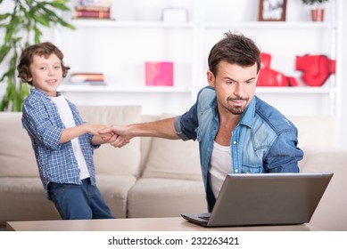 Son wants to spend time with his dad. Father is busy with work in computer.