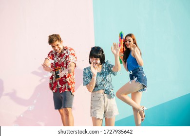 Songkran festival concept. Three people enjoy water festival in Songkran day. Isolated on pastel pink blue background. Portrait of three young thai people having fun in Songkran festival in Bangkok.