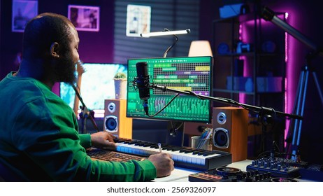 Songwriter taking notes to create new tracks for an album in his home studio, writing lyrics and harmonic elements before recording his song and editing on software, acoustical engineering. Camera B.