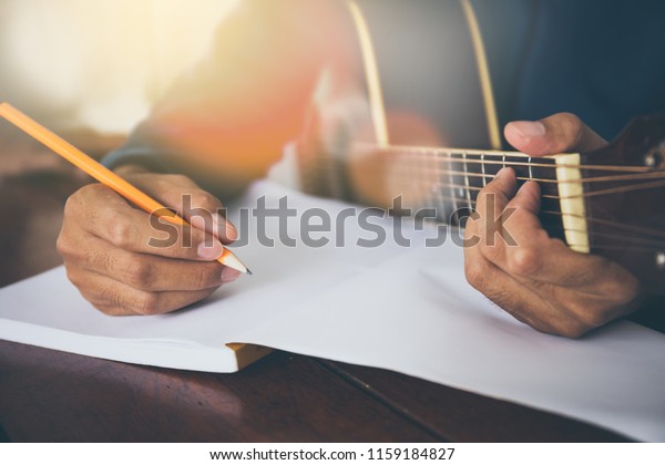 songwriter thinking and writing notes,lyrics\
in book at studio.man playing live acoustic guitar.concept for\
musician creative.artist composer in work process.people relaxing\
time with instrument