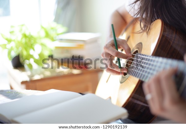 songwriter thinking and writing notes,lyrics in book at
studio.man playing live acoustic guitar.concept for musician
creative.artist composer in work process.people relaxing time with
instrument 