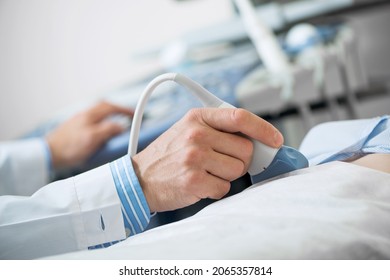 Sonogram procedure at modern hospital. Close-up doctors hand moving transducer on human belly. Professional clinical diagnostics and treatment. Ultrasound examination of human body internal organs