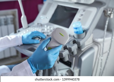 Sonographer holding ultrasound machine probe in clinic, closeup