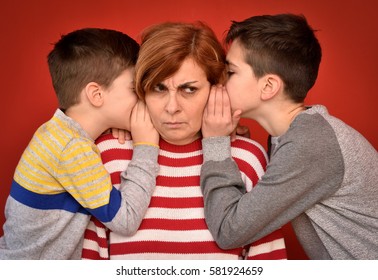 Sons whispering secret into ears of angry mother
