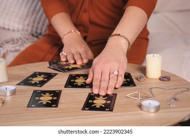 Soothsayer predicting future with tarot cards at table indoors, closeup
