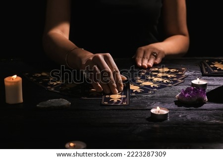 Soothsayer predicting future with tarot cards at table in darkness, closeup