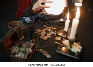 Soothsayer using crystal ball to predict future at table in darkness closeup